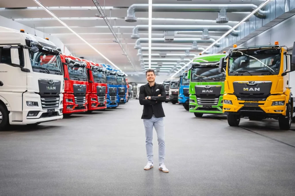 Mann steht lächelnd in riesiger MAN-Lkw-Produktionshalle