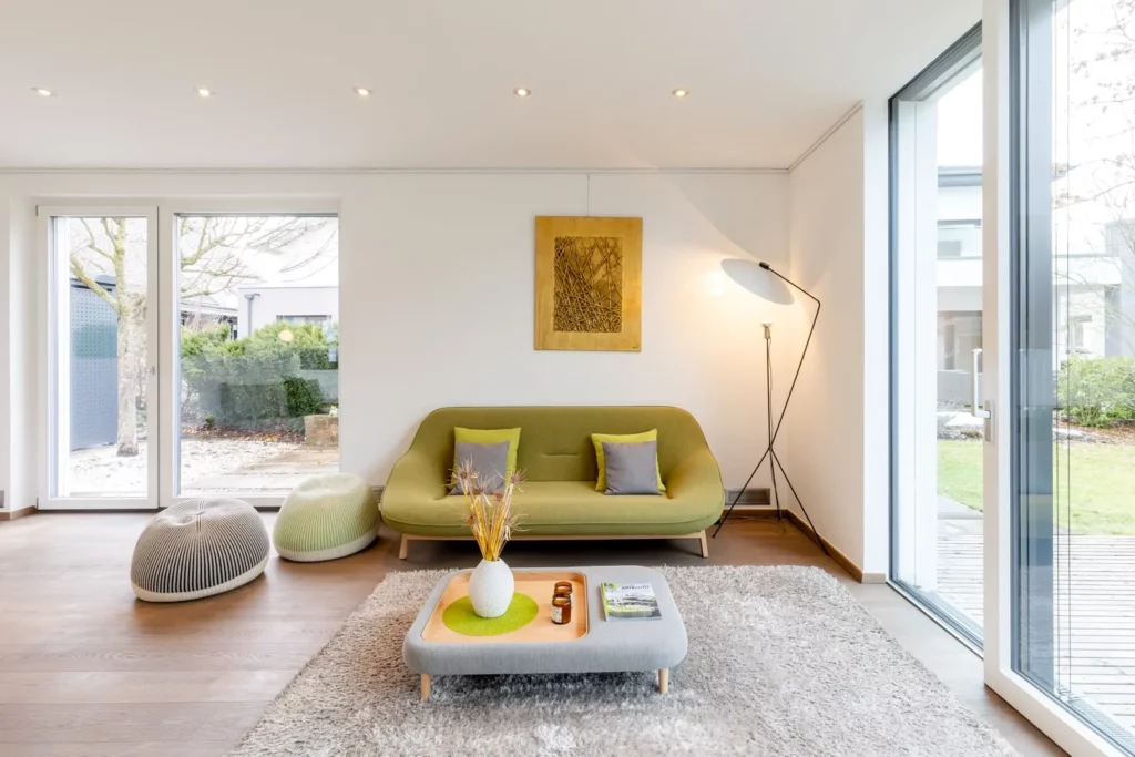 Modernes Wohnzimmer mit grüner Couch und großen Fenstern