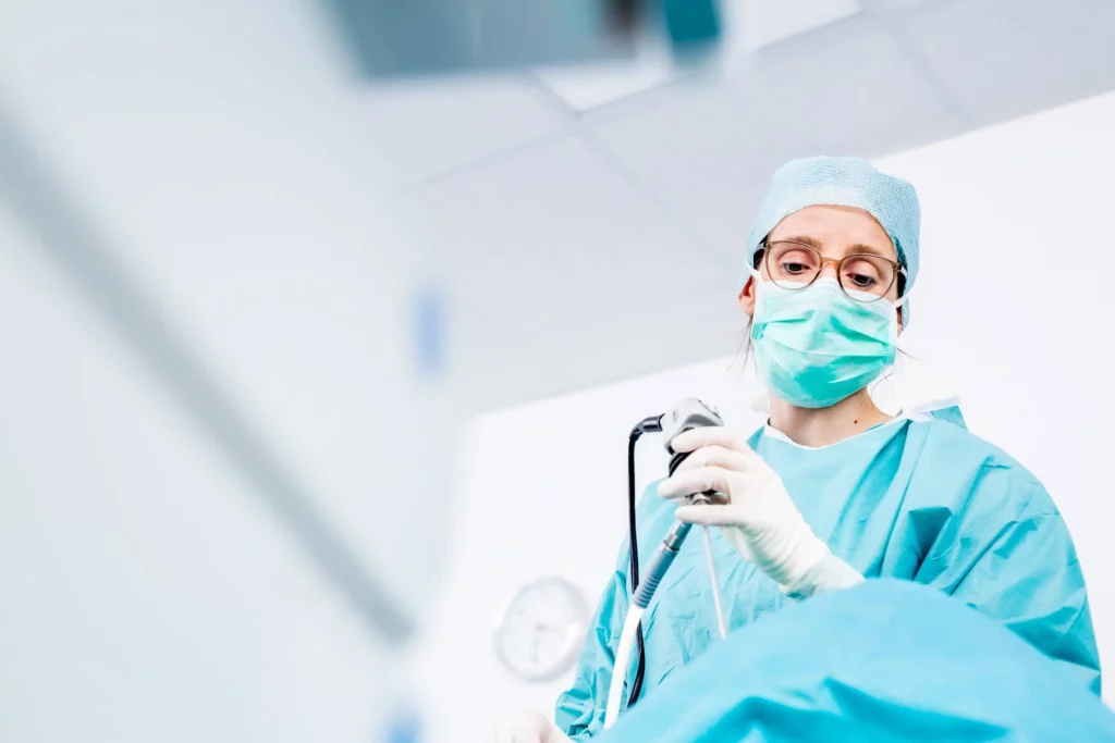 Ärztin in OP-Kleidung mit medizinischem Gerät im Operationssaal