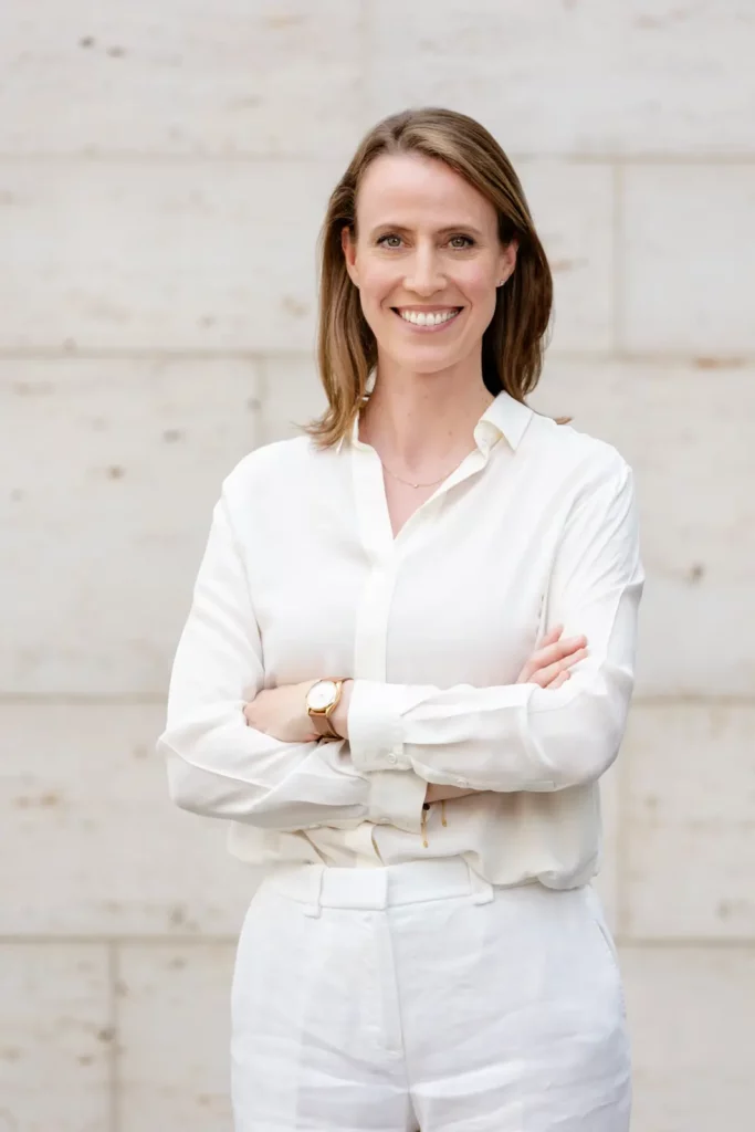 Lächelnde Frau in weißer Kleidung vor einer Steinwand