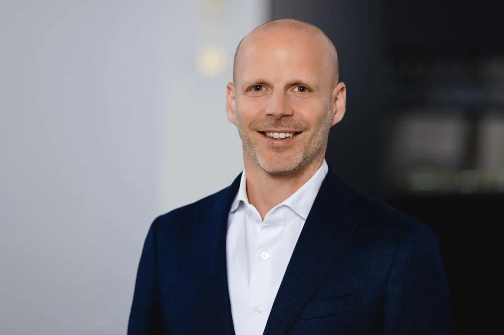 Lächelnder Mann im Anzug vor neutralem Hintergrund