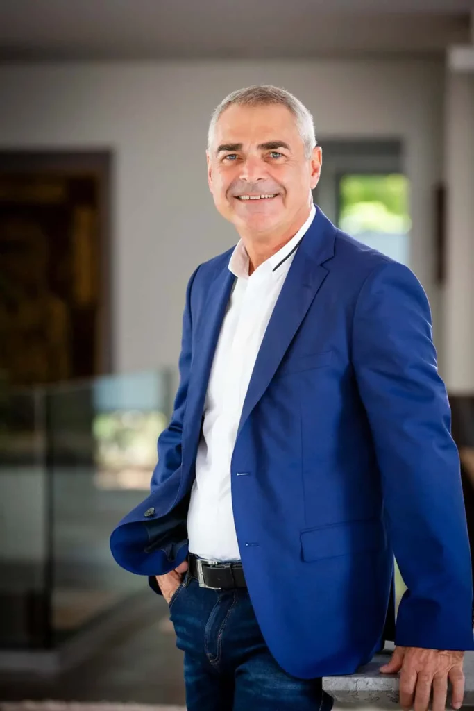 Älterer Mann in blauer Jacke lächelt in modernem Innenraum