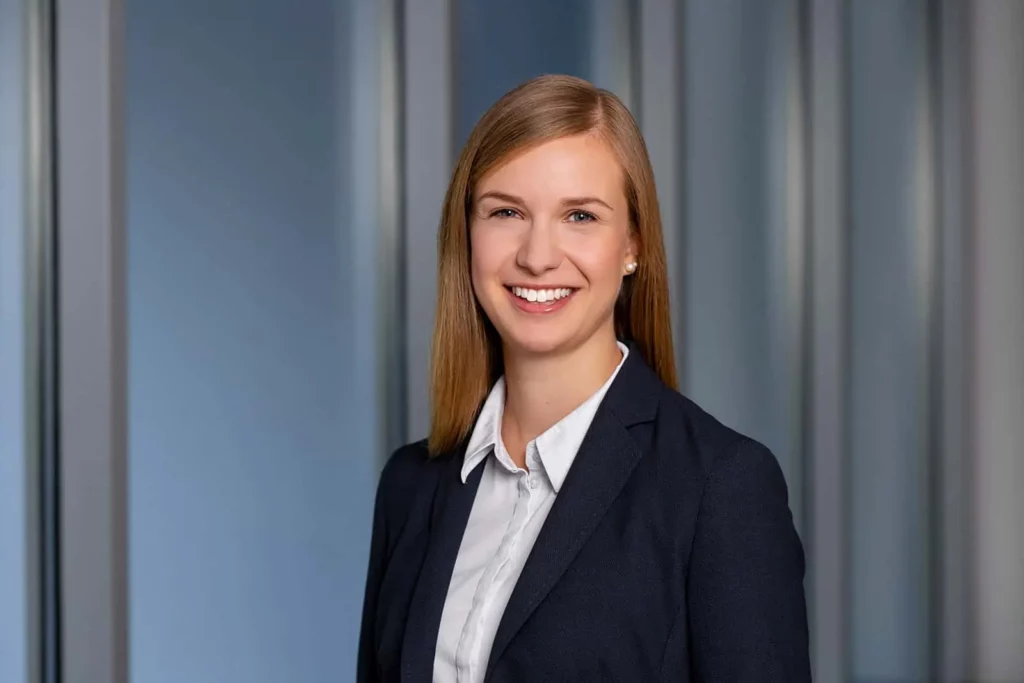 Porträt einer lächelnden Frau in Business-Kleidung vor Glaswand