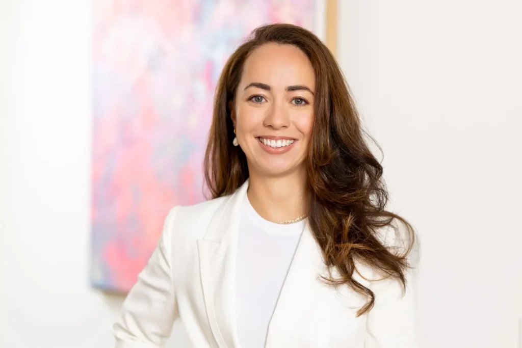 Junge Frau in weißen Blazer vor abstraktem Kunstwerk