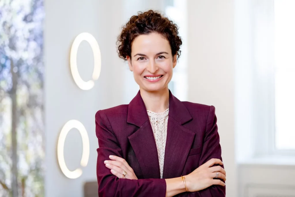 Frau in lila Blazer lächelt mit verschränkten Armen