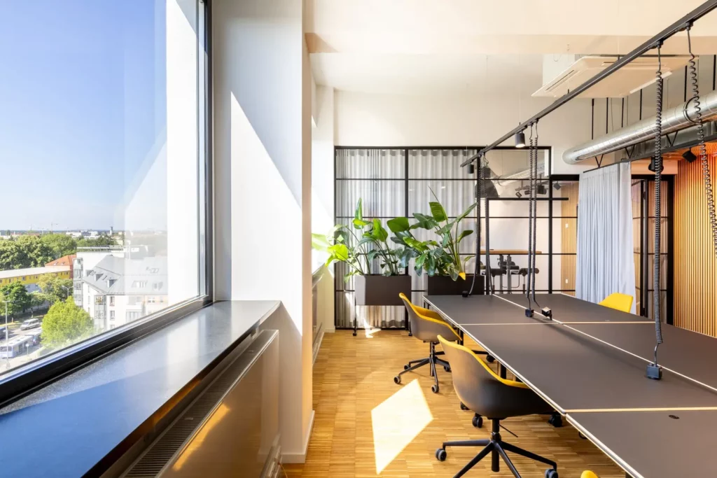 Modernes Büro mit großem Fenster, Pflanzen und gelber Bürostühlen