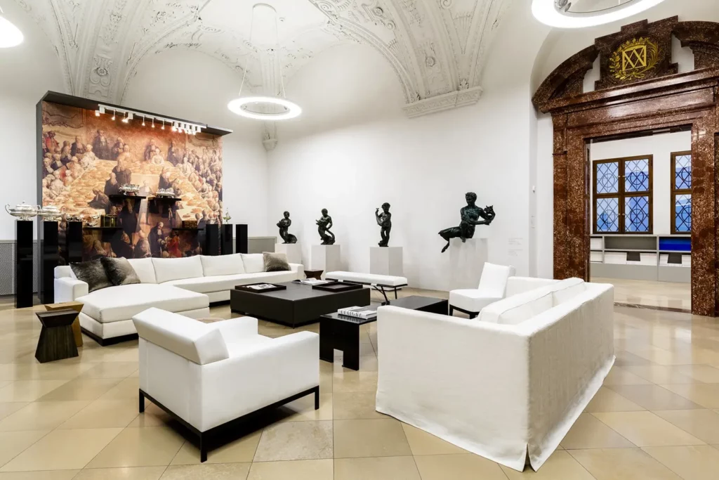 Elegantes Wohnzimmer mit weißen Sofas und Skulpturen in historischem Raum