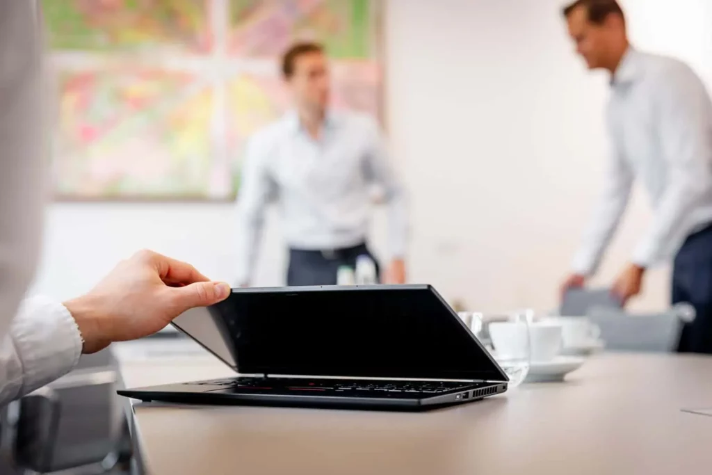 Laptop im Büro mit zwei Männern im Hintergrund