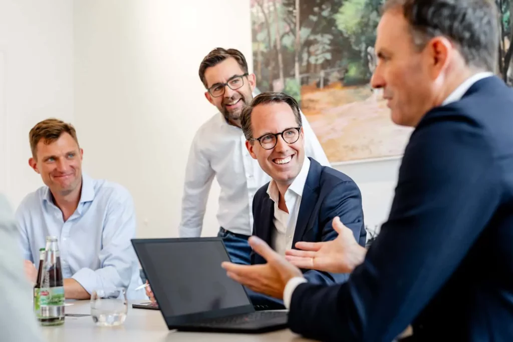 Geschäftstreffen mit vier lächelnden Geschäftsleuten am Konferenztisch