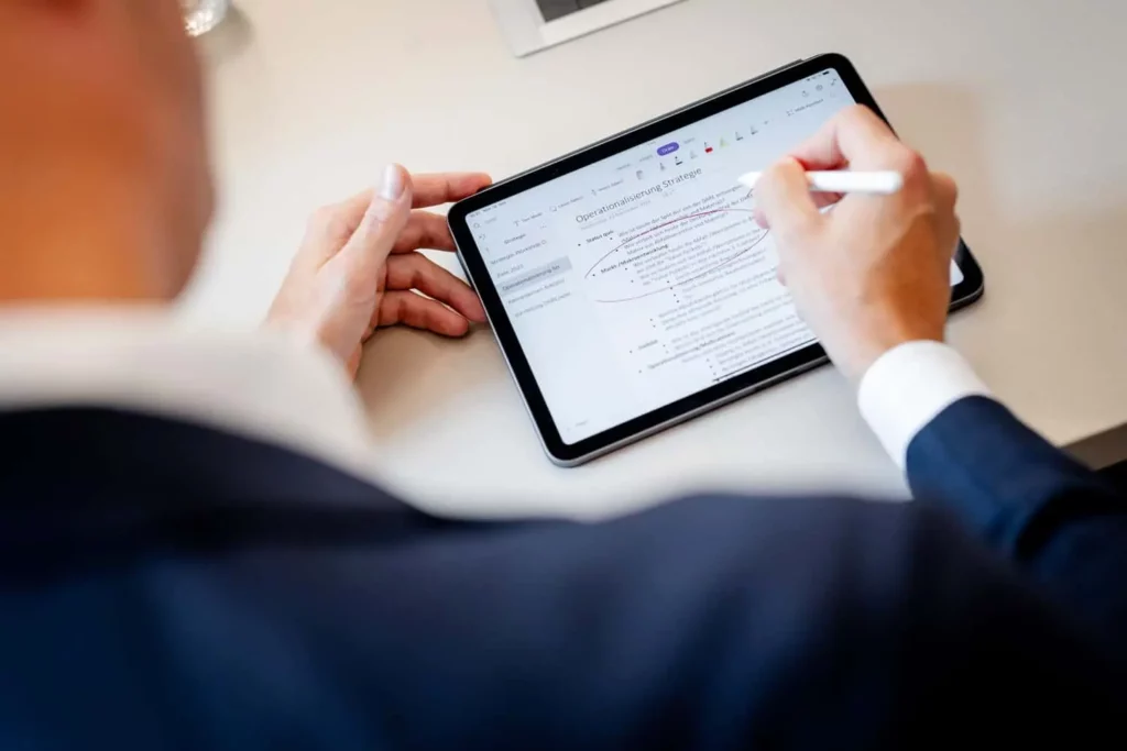 Person schreibt mit Stift auf Tablet beim Arbeiten im Büro