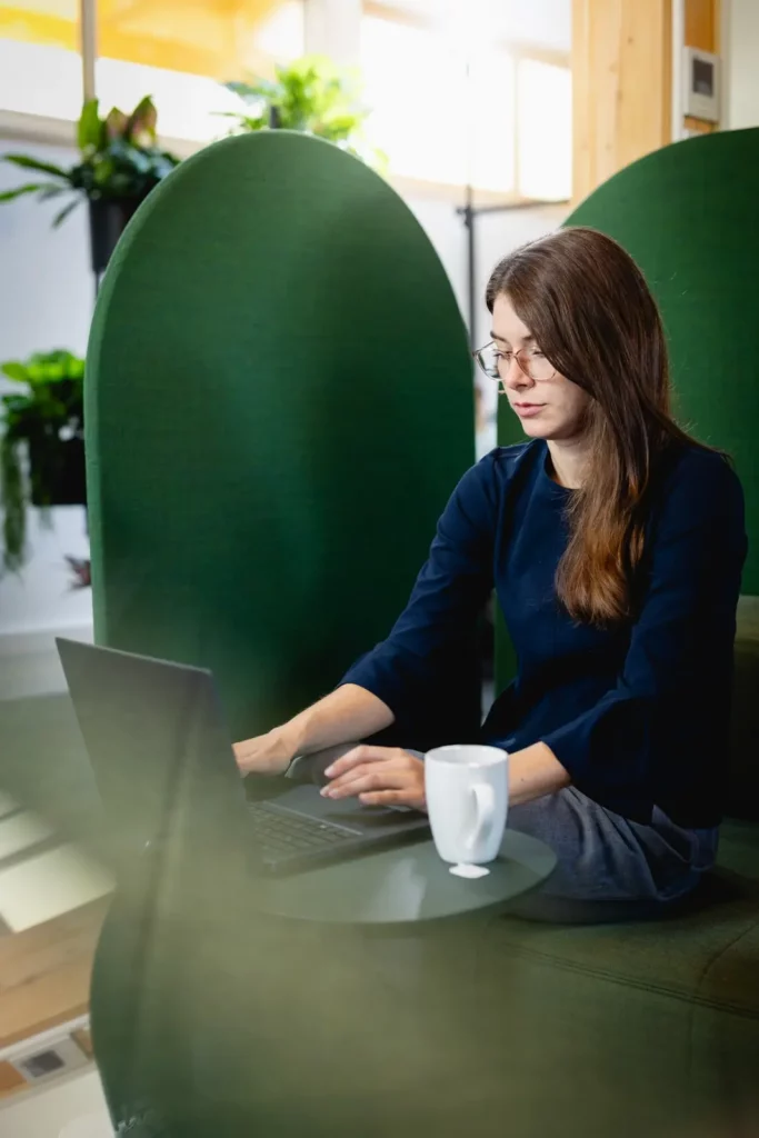 Frau arbeitet an Laptop in modernem Büro mit Pflanzen