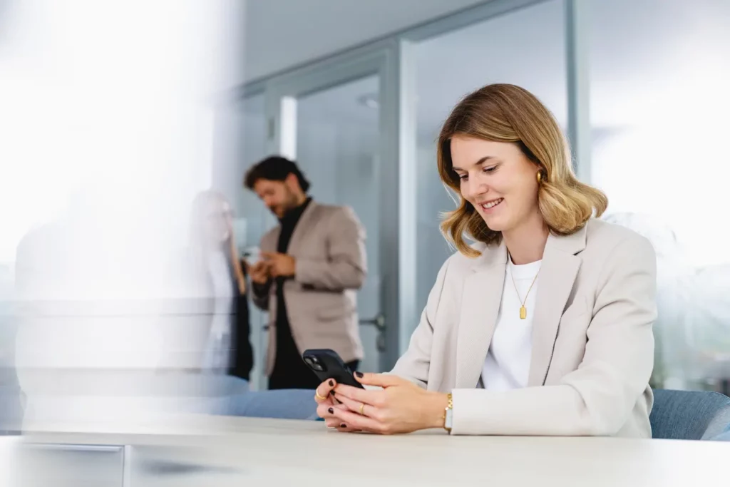 Geschäftsfrau in modernem Büro mit Smartphone