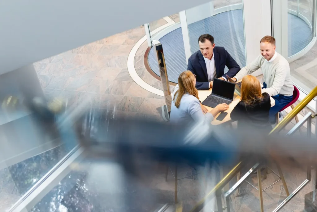 Geschäftstreffen von vier Personen am runden Tisch in modernem Büro