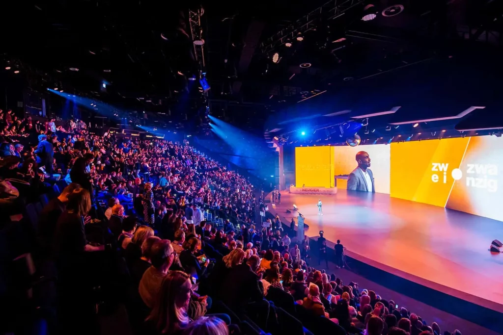 Große Konferenz mit vollem Auditorium und Präsentation auf großer Leinwand