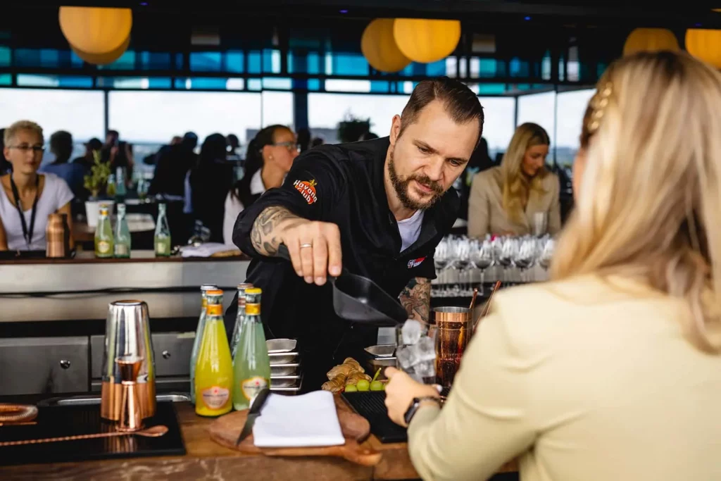 Barkeeper gießt Getränk für Gast in moderner Bar mit Getränken