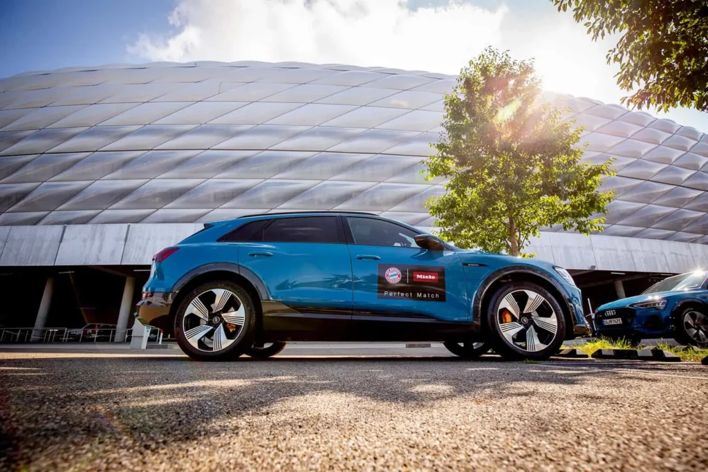 Blauer Audi E-Tron vor der Allianz Arena in München