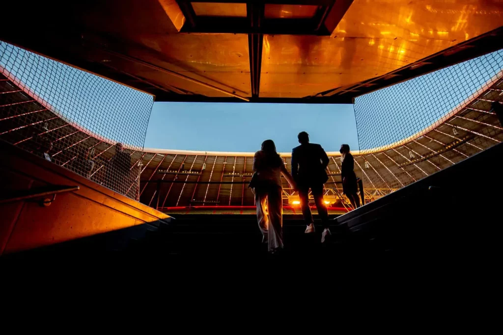 Silhouetten von Menschen betreten ein Stadion bei Sonnenuntergang