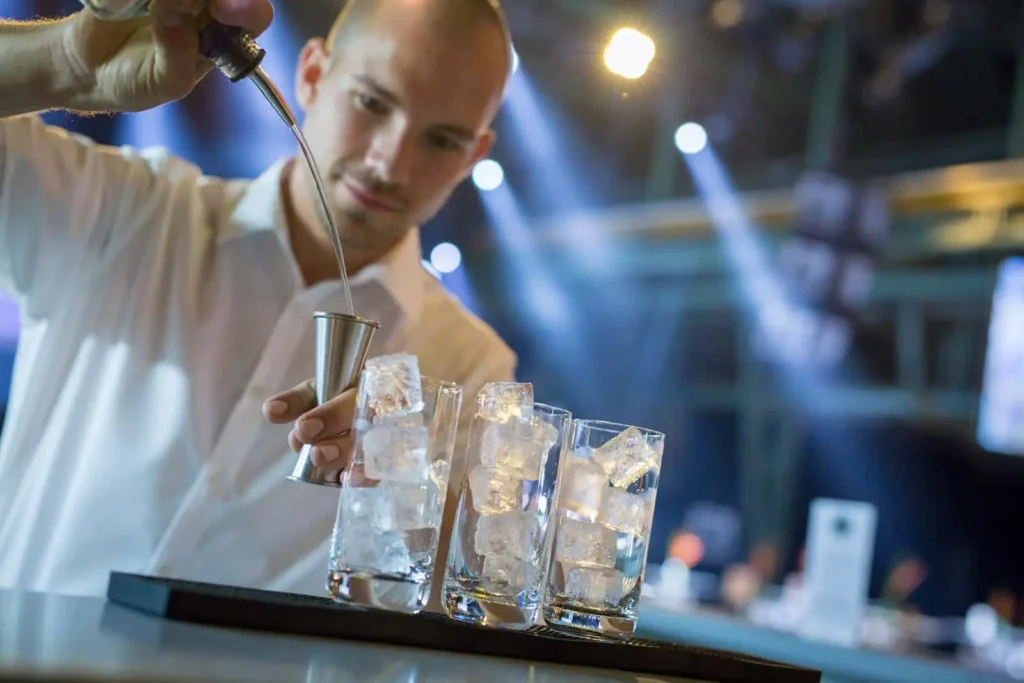 Barkeeper gießt Eis in Gläser auf einer Party ein