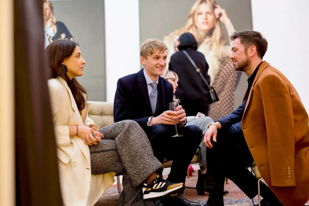 Menschen in stilvoller Kleidung unterhalten sich in einer modernen Kunstgalerie