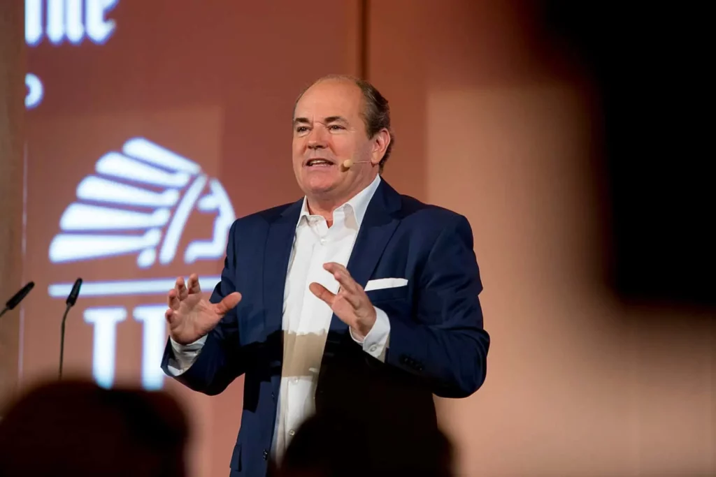 Mann hält Vortrag mit Mikrofon auf Bühne