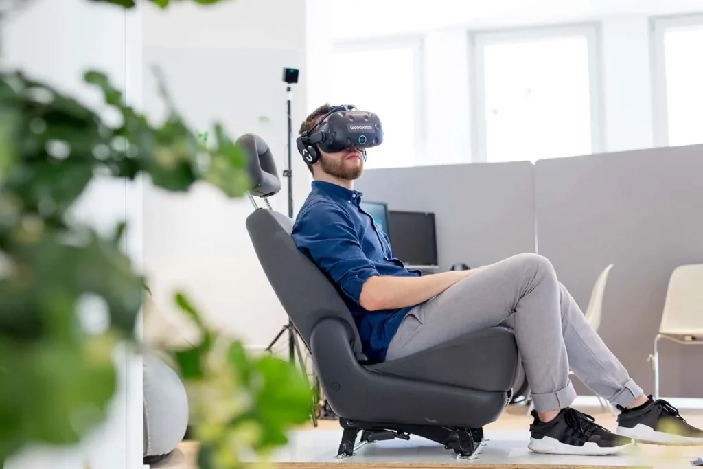 Mann in modernem Büro mit VR-Headset auf ergonomischem Stuhl