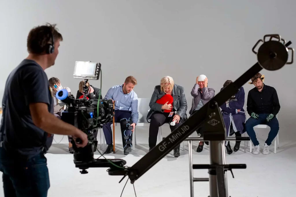 Menschen beim Filmdreh vor einer Kamera auf Stühlen