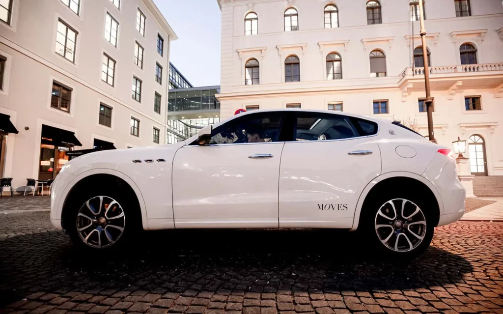 Weißer SUV auf Kopfsteinpflaster vor historischer Gebäudeansicht