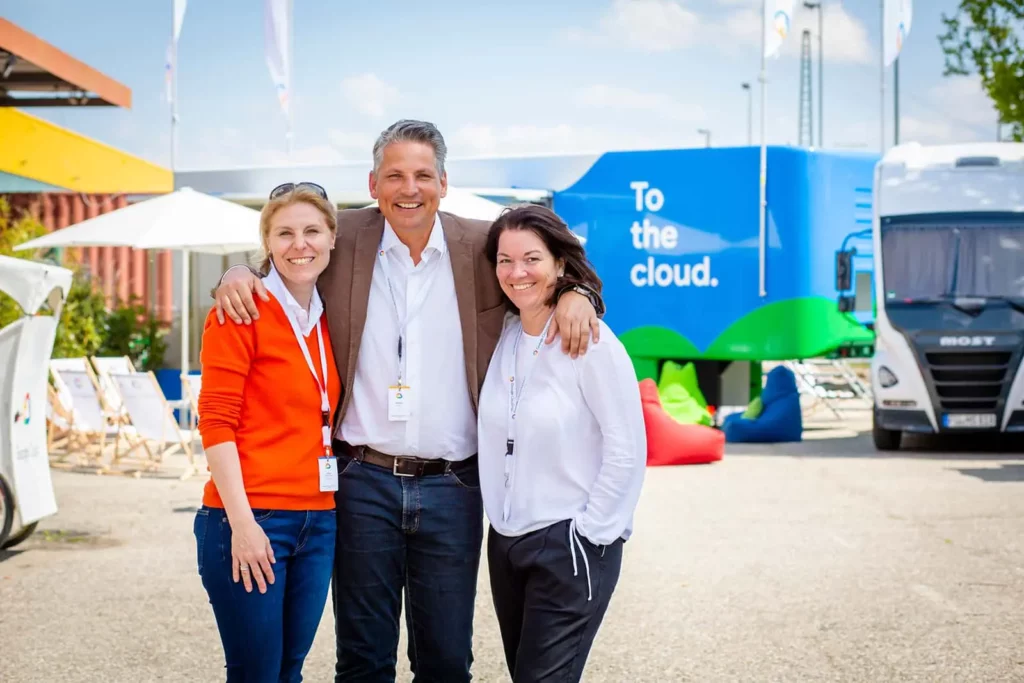 Drei Menschen vor einem bunten LKW auf einer Wiese
