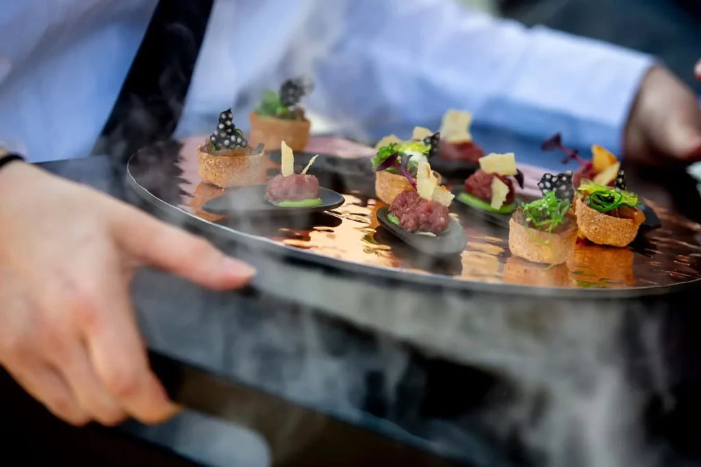 Gourmet-Vorspeisen auf Tablett serviert von Kellner in elegantem Ambiente