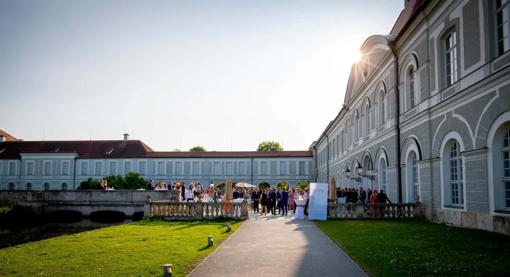 Hochzeitsgesellschaft vor Schloss in sonniger Umgebung