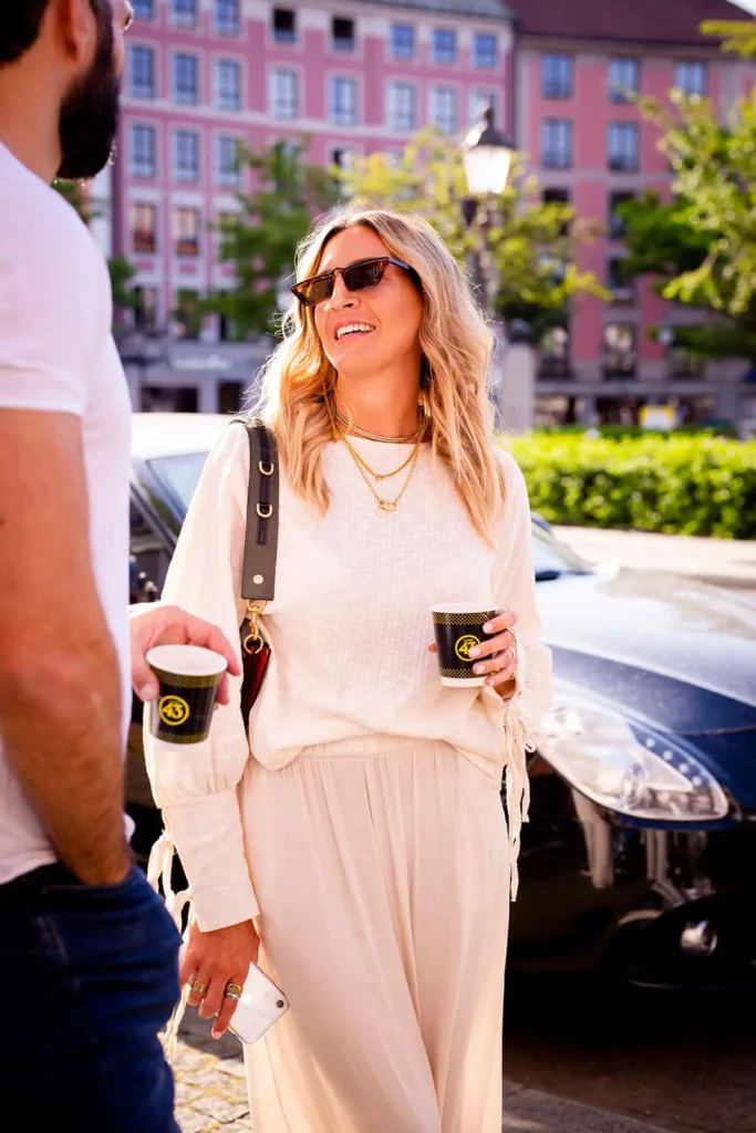 Glückliche Frau im Freien mit Sonnenbrille und Kaffee im Sommer