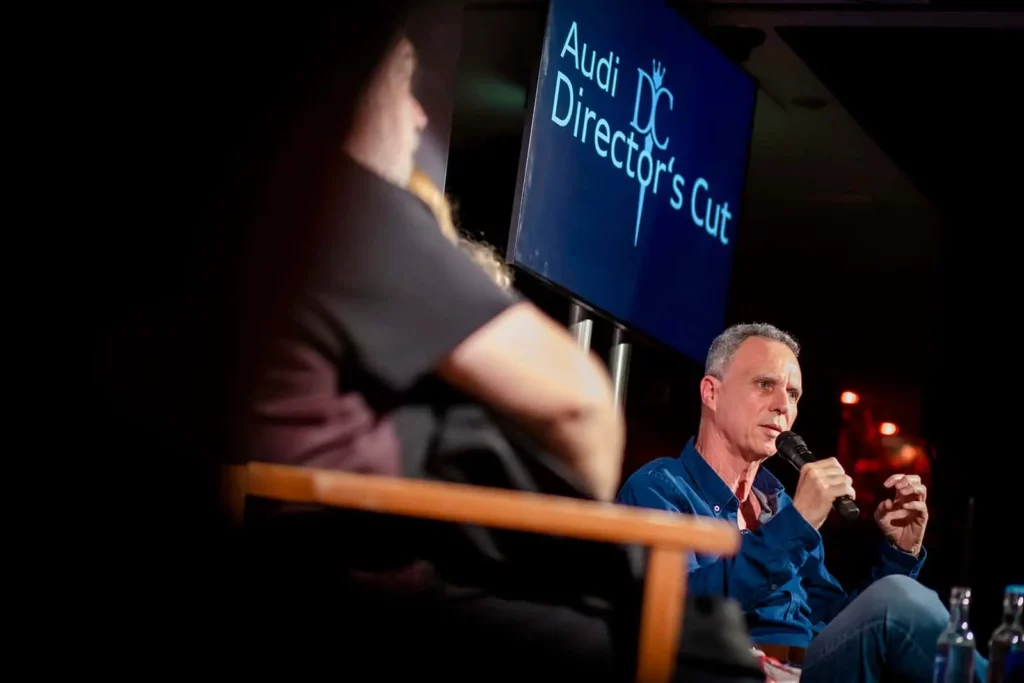 Mann spricht bei Veranstaltung mit Audi Director's Cut Schild im Hintergrund