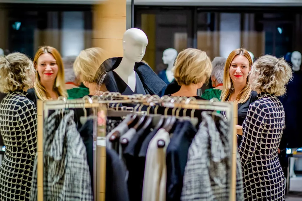 Zwei Frauen betrachten Mode im eleganten Geschäft mit Spiegeln