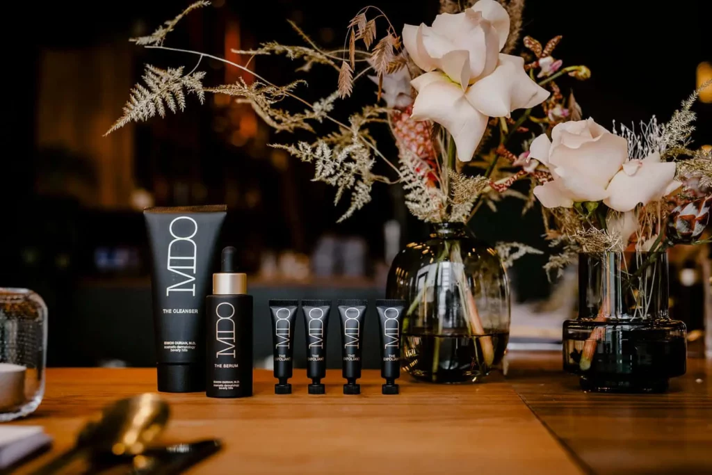 Luxuriöse Hautpflegeprodukte von MDO mit Blumenarrangement auf Holztisch