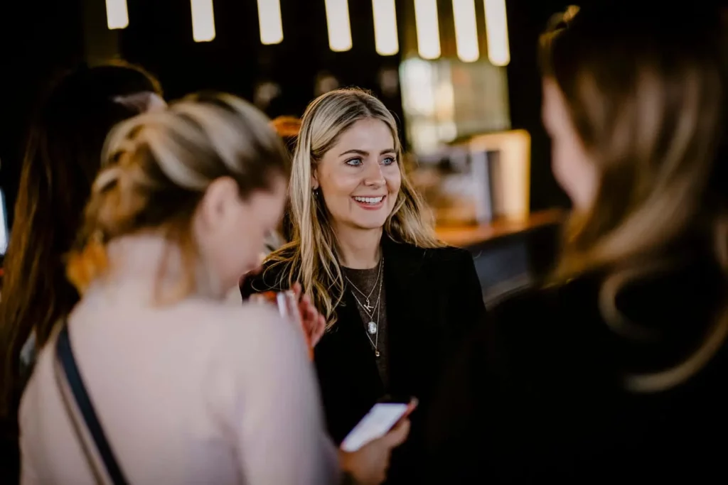 Lächelnde Frau bei einer Veranstaltung mit anderen Teilnehmern