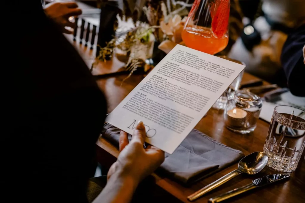 Person studiert Menü an elegantem Restauranttisch