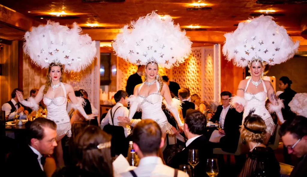 Tänzerinnen in glamourösen Kostümen mit Federkopfbedeckungen bei einer Abendveranstaltung