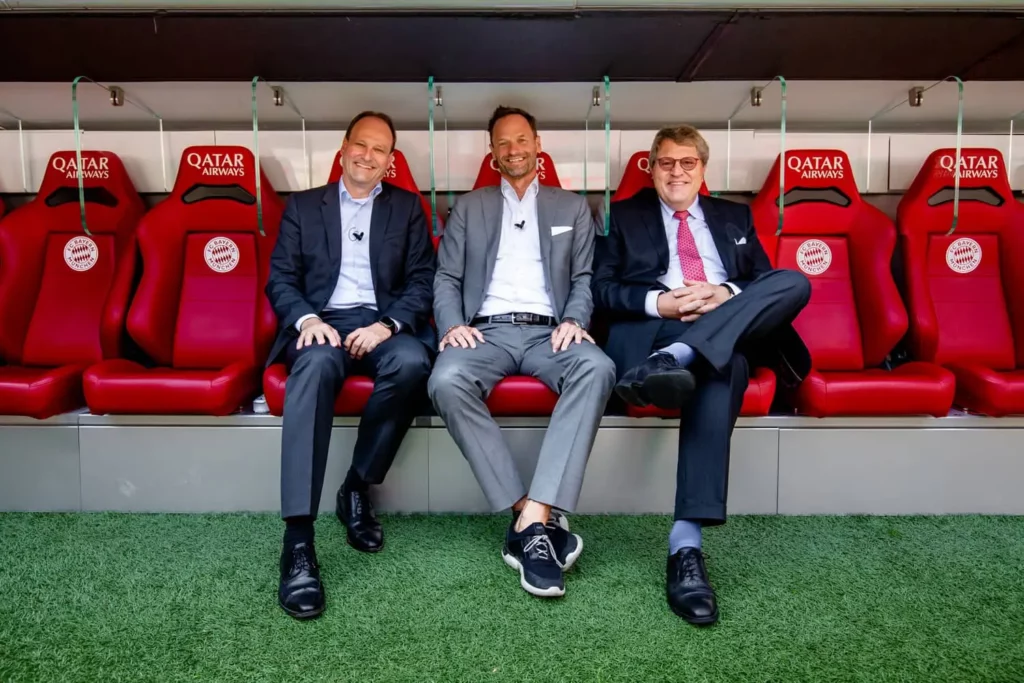 Drei Männer im Anzug sitzen auf der Bayern München Trainerbank