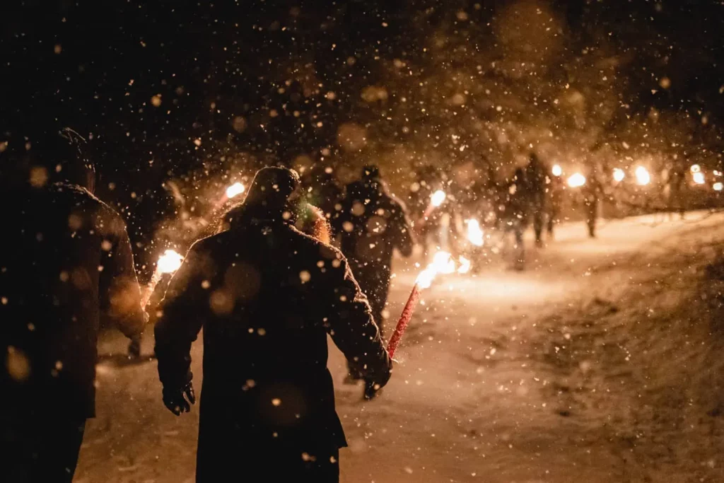 Menschen marschieren nachts im Schnee mit Fackeln