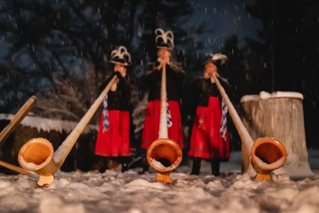 Alphornbläserinnen in traditioneller Tracht im winterlichen Schneefall