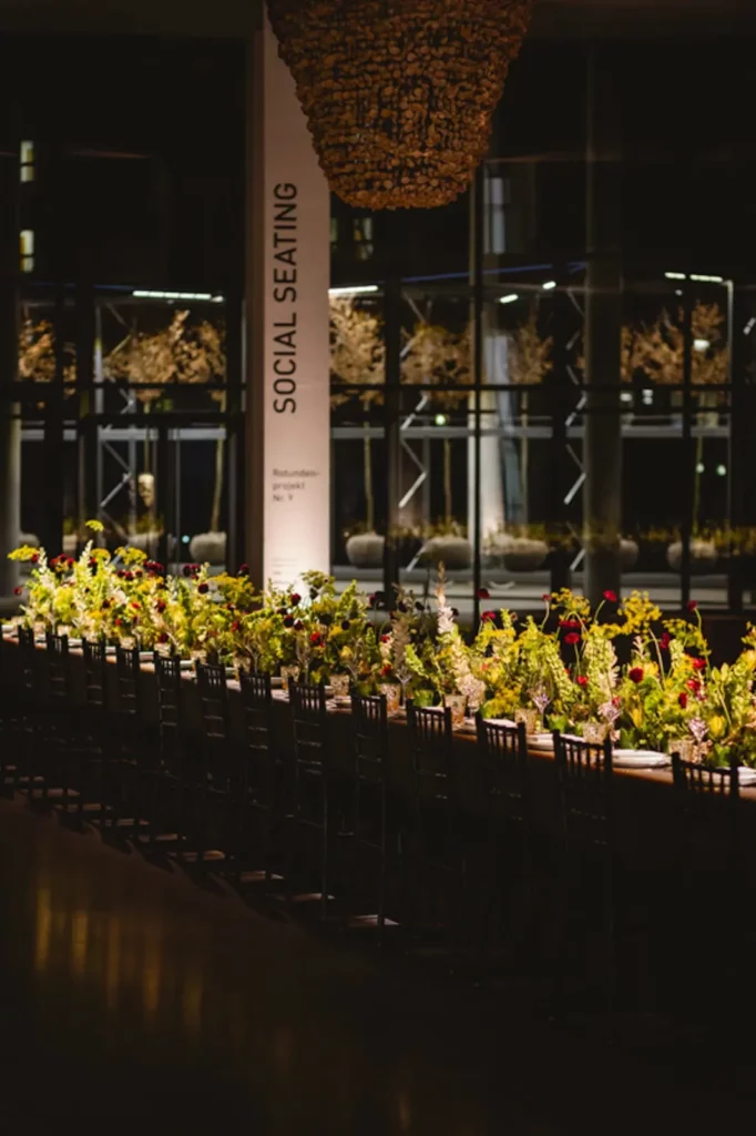 Lange, mit Blumen dekorierte Tafel in elegant beleuchteter Umgebung