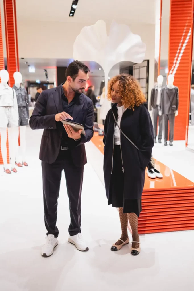 Mann im Anzug und Frau schauen auf Tablet in moderner Boutique