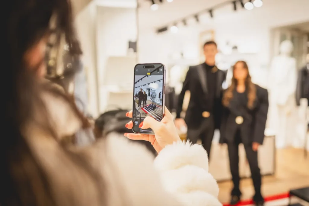 Person fotografiert zwei stilvoll gekleidete Menschen im Modegeschäft