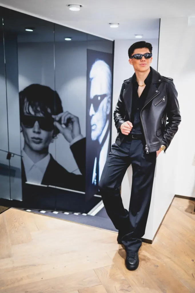 Mann in schwarzer Lederjacke posiert vor Modeporträt im Geschäft