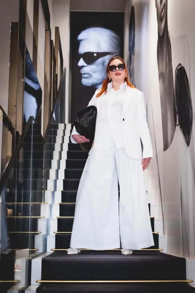 Frau in weißem Hosenanzug auf schwarzer Treppe, Modernes Modeporträt