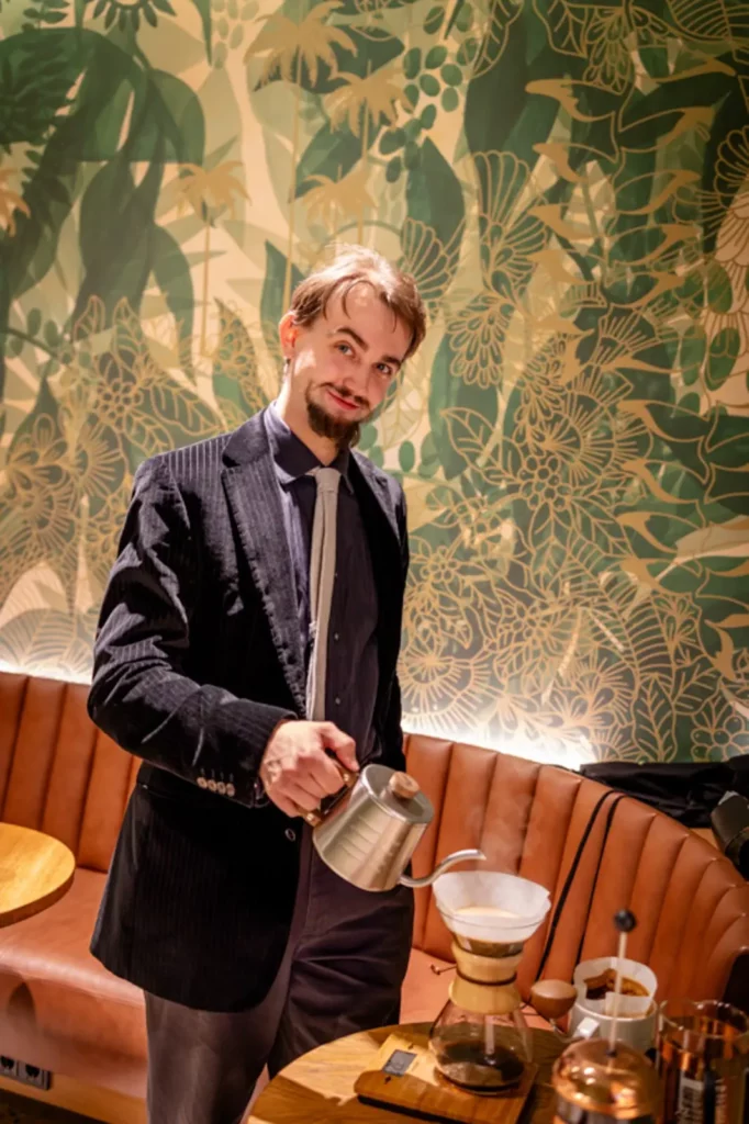 Mann in Café gießt Wasser in Chemex-Kaffeebereiter