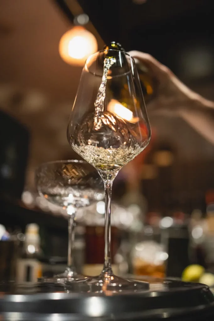 Weißwein wird in ein elegantes Weinglas in einer stilvollen Bar eingeschenkt
