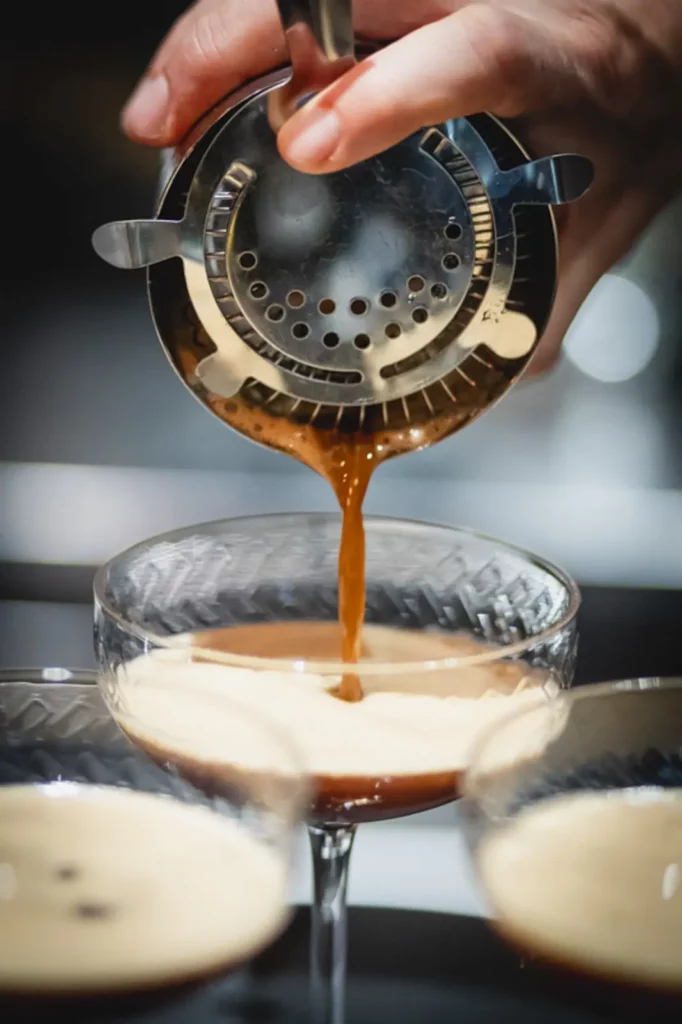 Zubereitung eines perfekten Espresso Martini mit Sieb und Gläsern