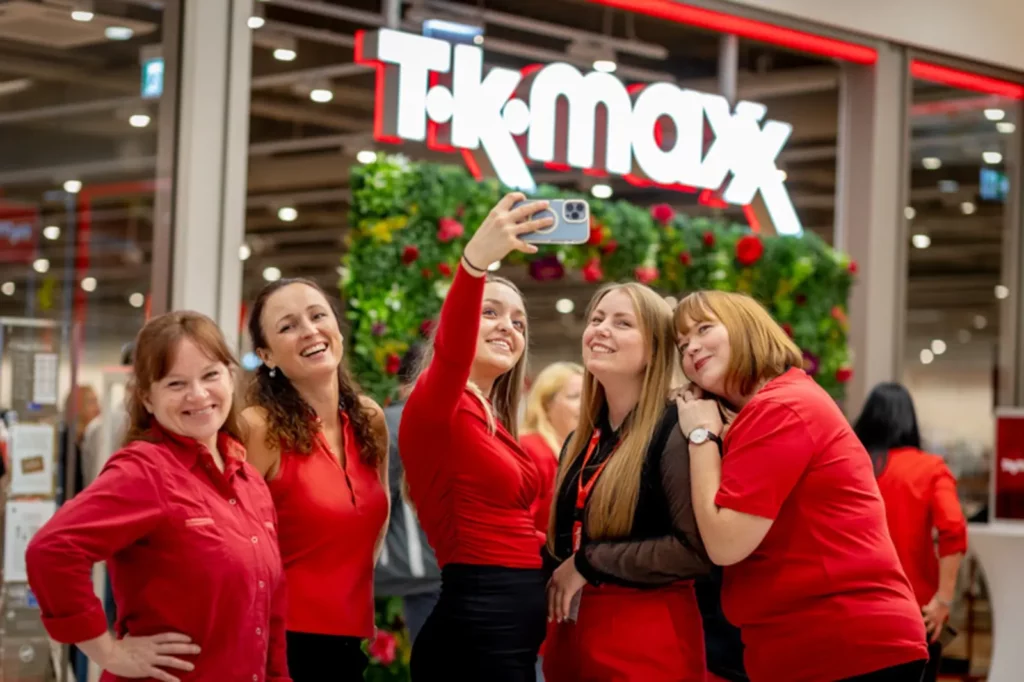 Gruppe lächelnder Frauen in roten Outfits vor einem TK Maxx Laden
