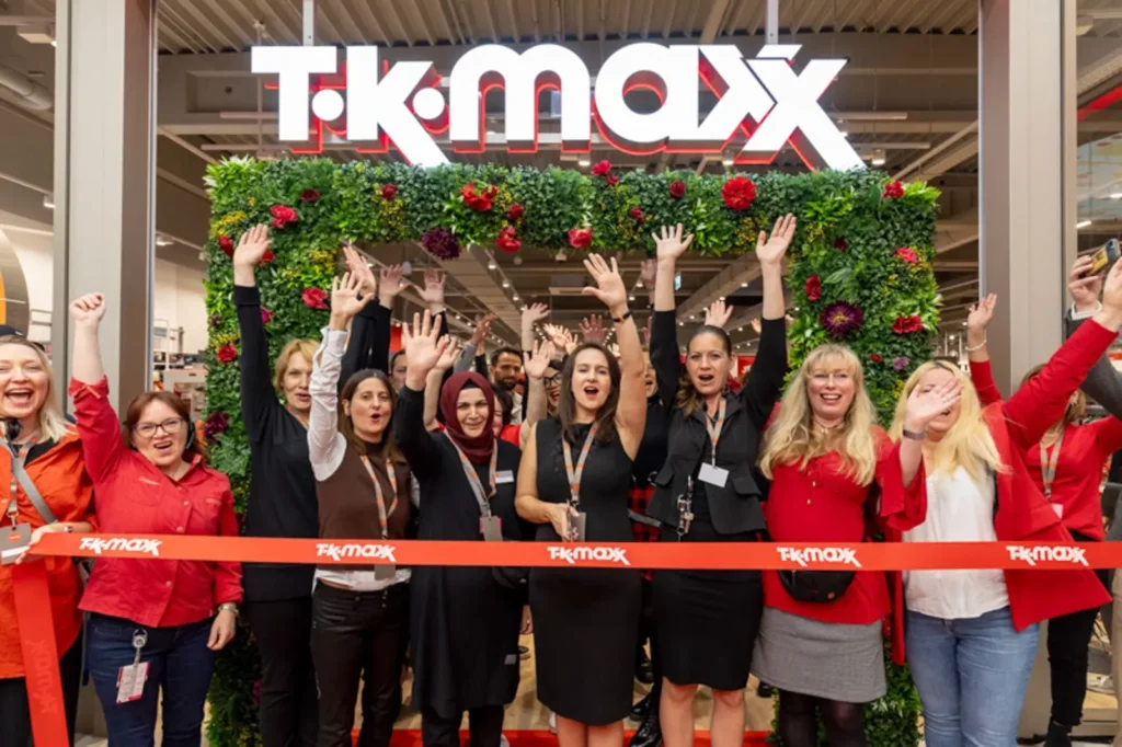 Mitarbeiter feiern die Eröffnung eines T.K. Maxx Ladens mit einem roten Band.